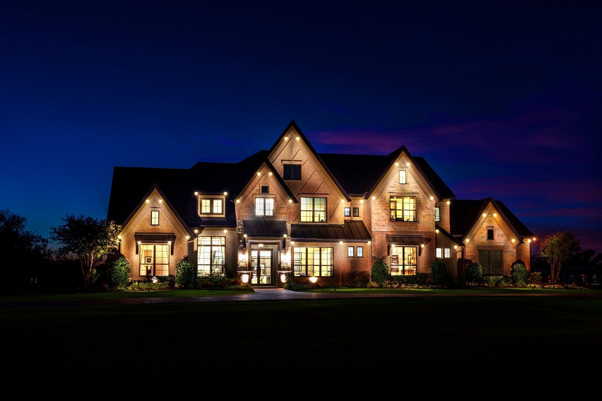 Large home at night with warm white roofline lights for everyday architectural lighting.